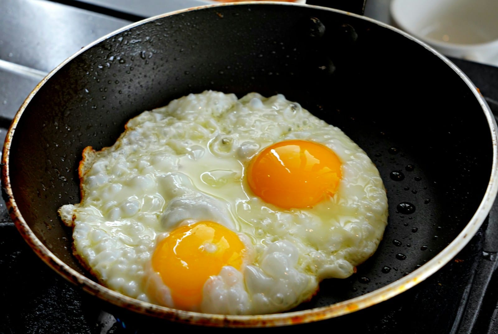 Photo by hartono subagio Two fried eggs sizzling in a black pan
