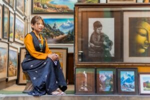 Woman sitting in art gallery surrounded by paintings